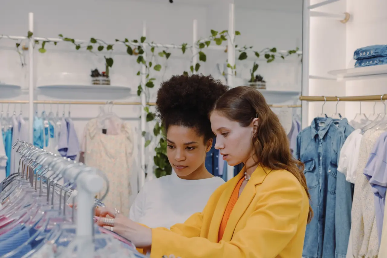 Two shoppers browsing clothes on a rail in a boutique
